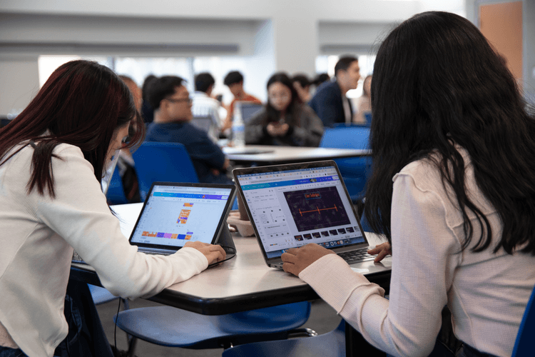 Students gathered around laptops at an RCC event
